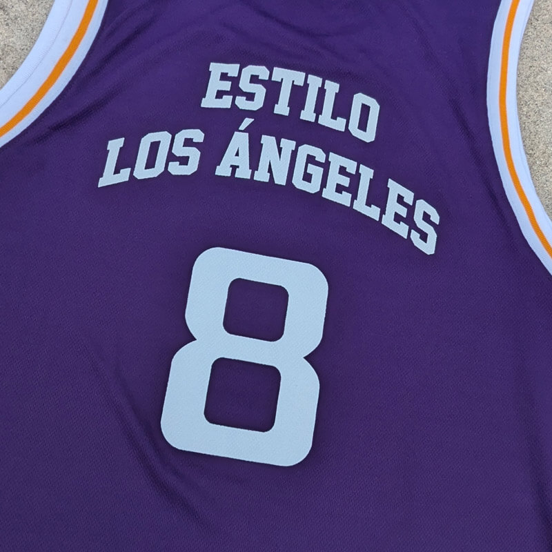 Close-up of white Estilo Los Angeles lettering and number 8 on the purple jersey