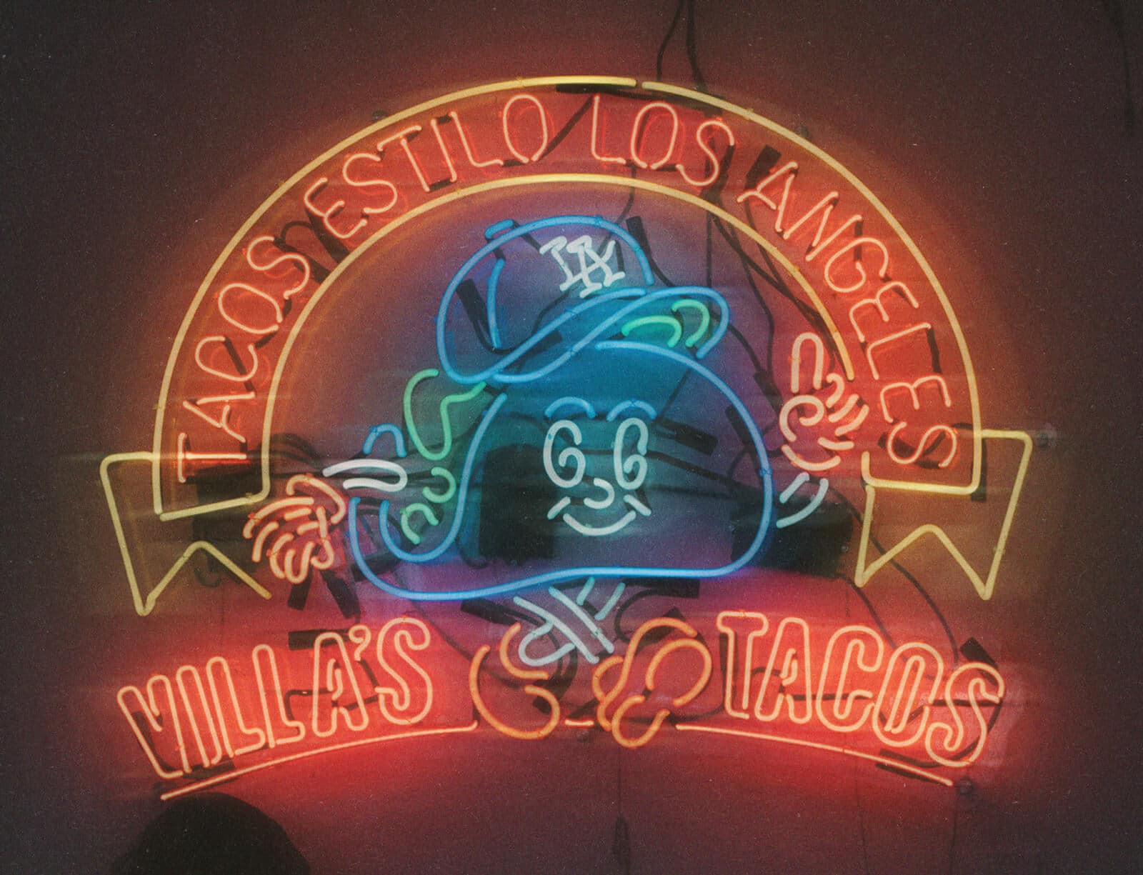 Villa's Tacos neon sign with smiling taco mascot