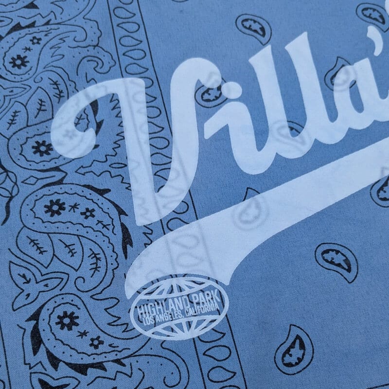 Close-up of pale Villa’s lettering and dark paisley pattern on the blue bandana